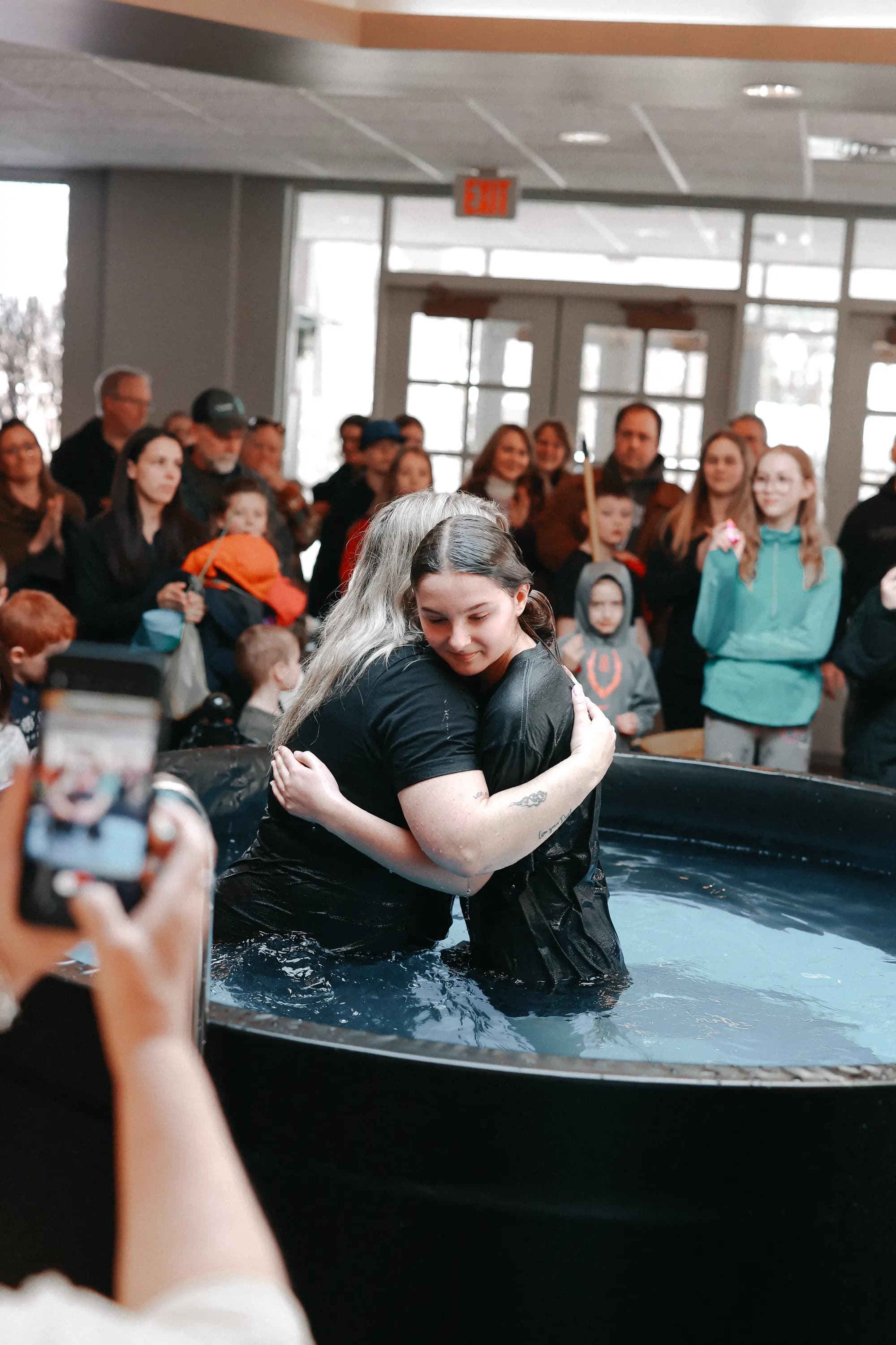 A hug in the baptism tank in front of the church family