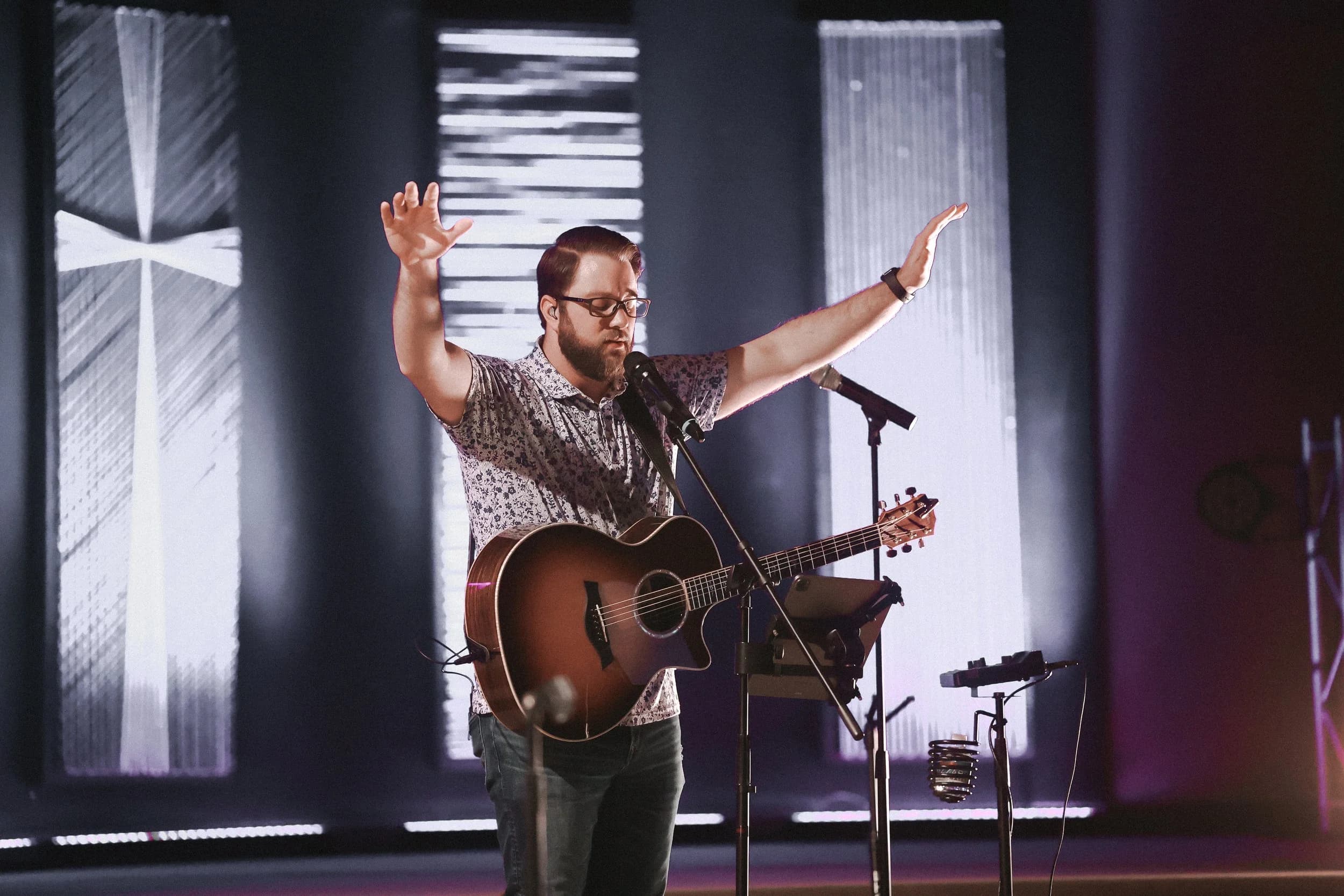 Worship leader singing with hands raised