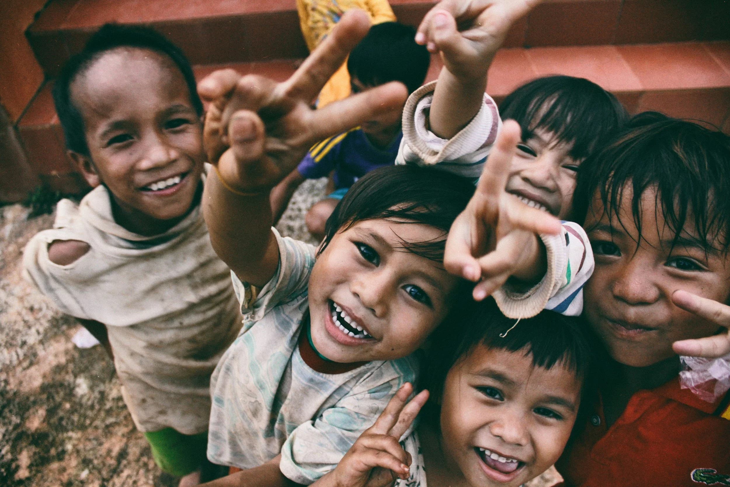 Children smiling and holding up peace signs