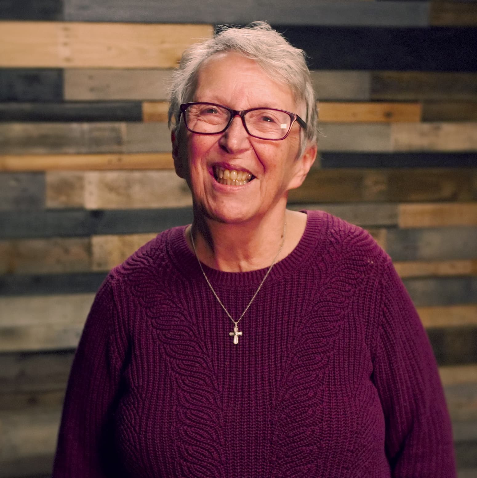 Trudy Bisson smiling in front of a wooden wall